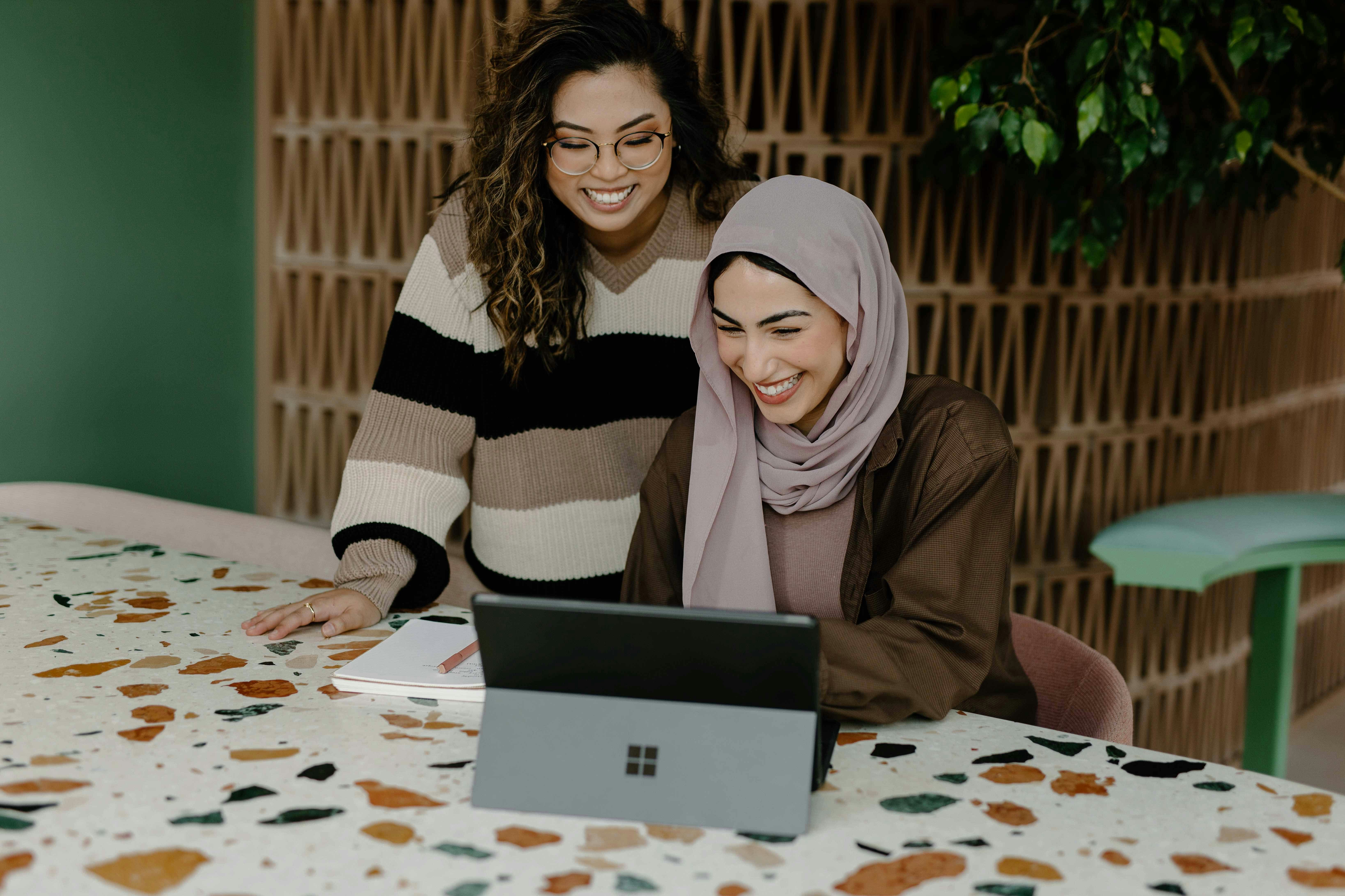 Two colleagues collaborating on a laptop at a modern workspace